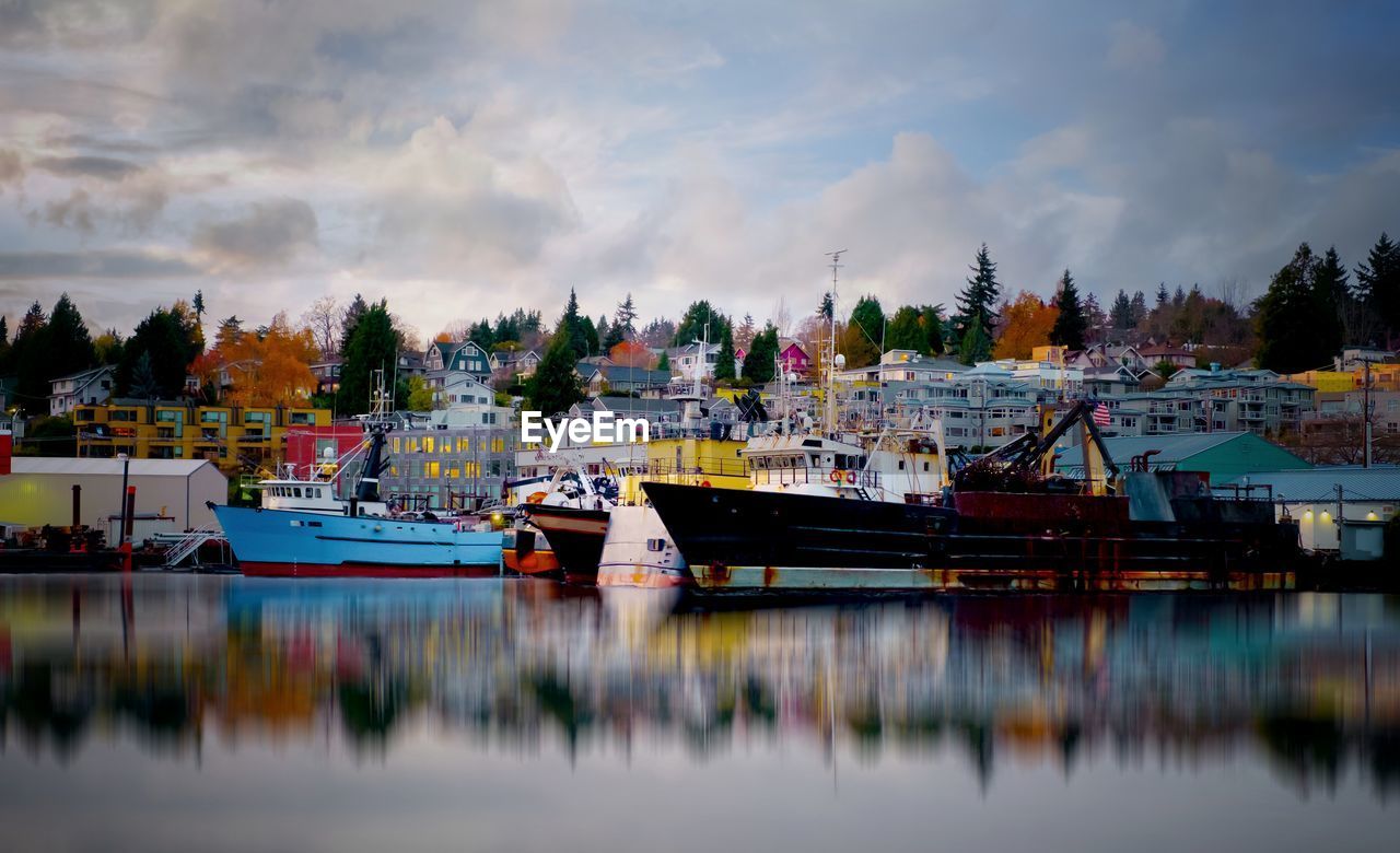 Boats moored at harbor against sky