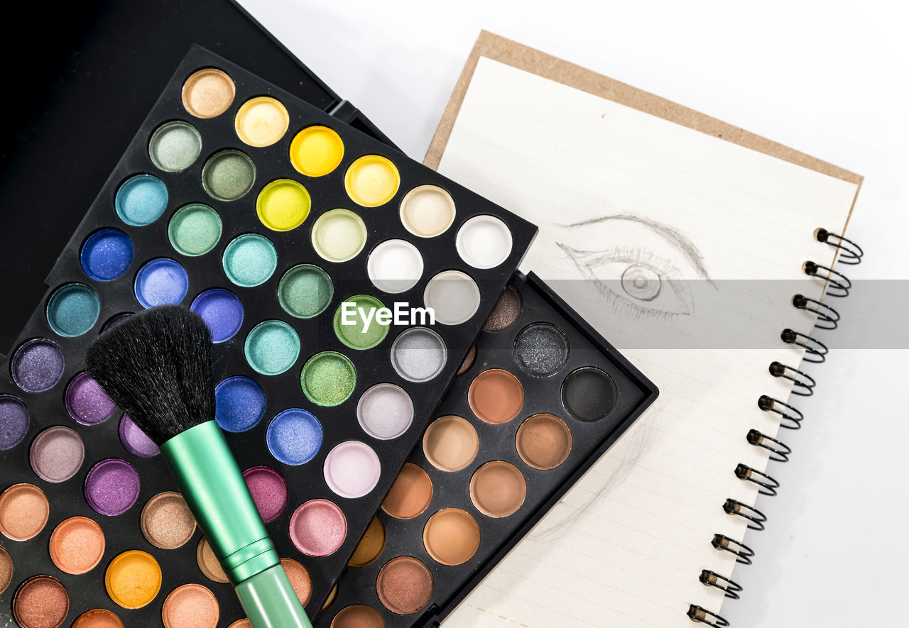 Close-up of eyeshadow and brush over book