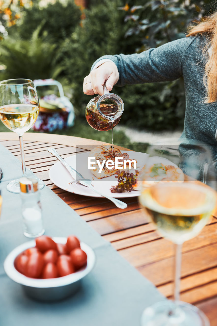 Family and friends having meal - pizza, salads, fruits and drinking white wine during summer picnic