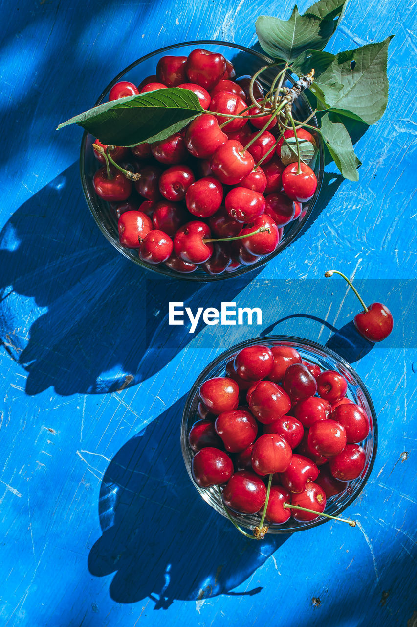 fruit, healthy eating, food and drink, food, red, plant, wellbeing, freshness, blue, berry, produce, high angle view, no people, cherry, painting, nature, leaf, still life, bowl, juicy, plant part, wood, blue background, strawberry, indoors, ripe, organic, studio shot, container, directly above