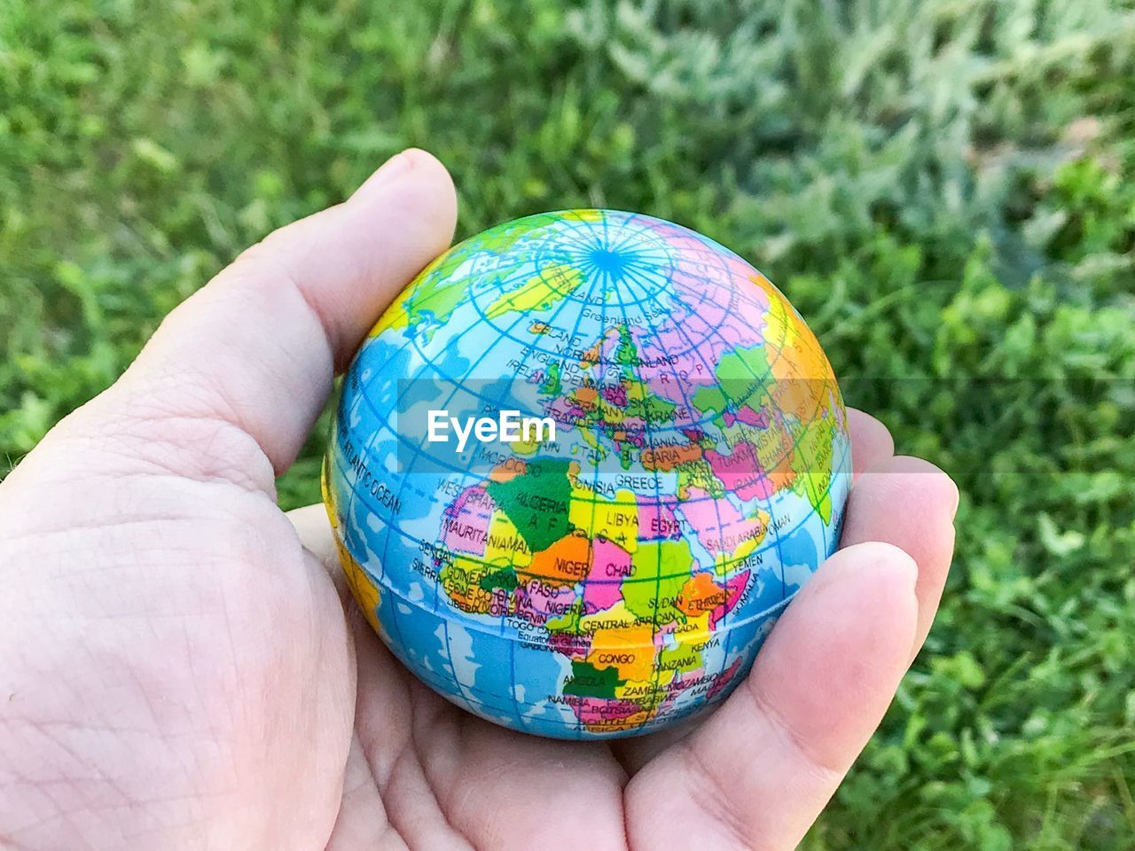 Close-up of person holding globe over grass