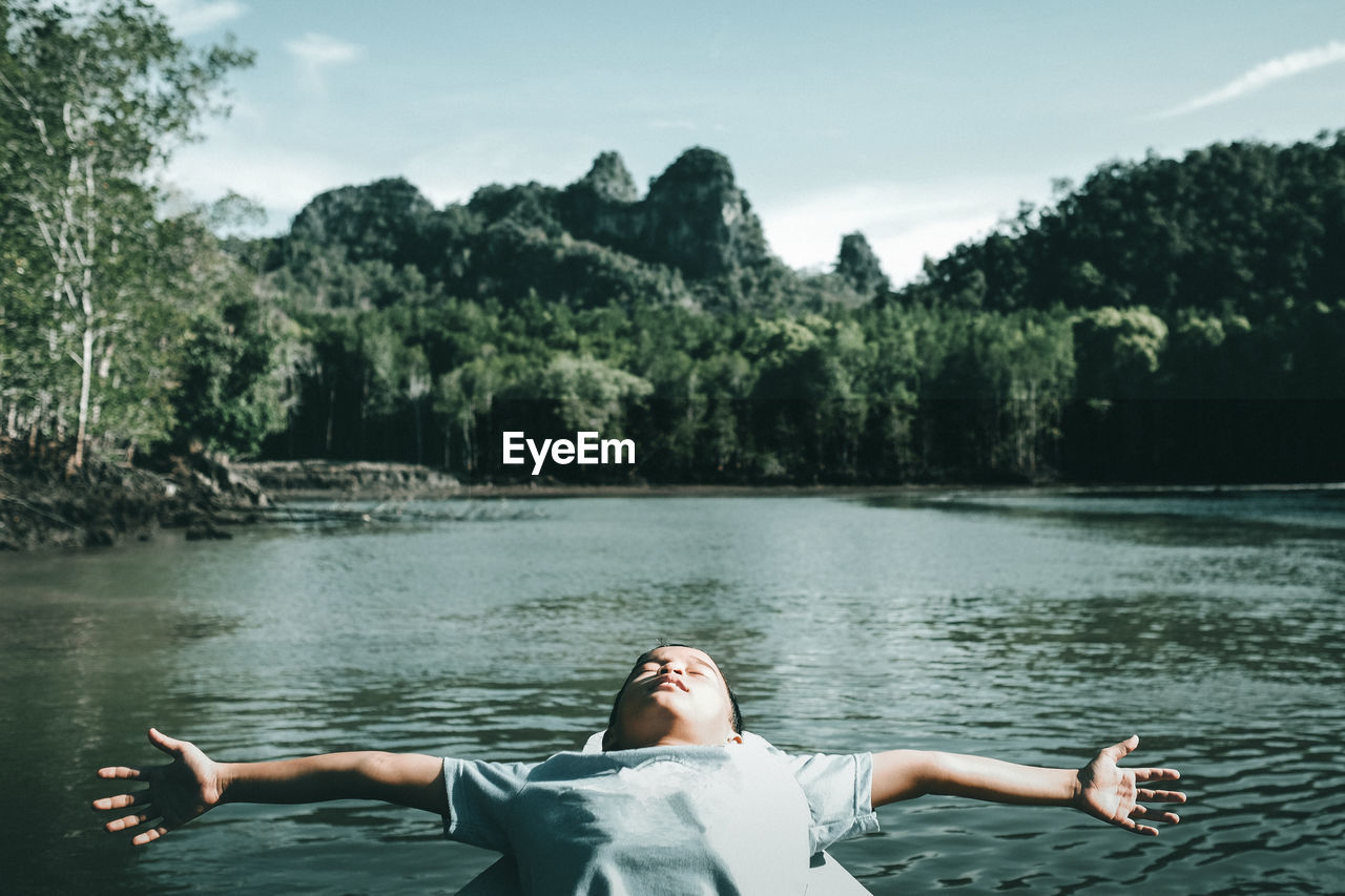 Boy in boat at lake against sky