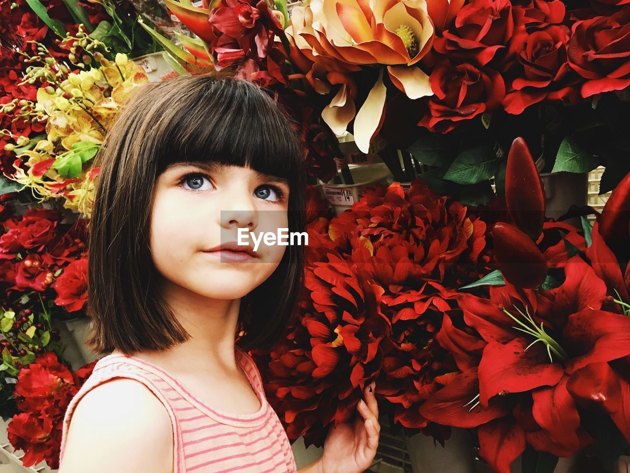 Close-up of girl by artificial flowers in shop