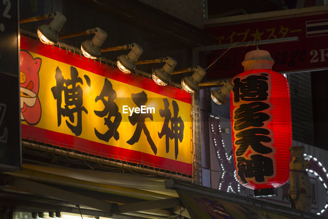 LOW ANGLE VIEW OF TEXT ON ILLUMINATED SIGN BOARD