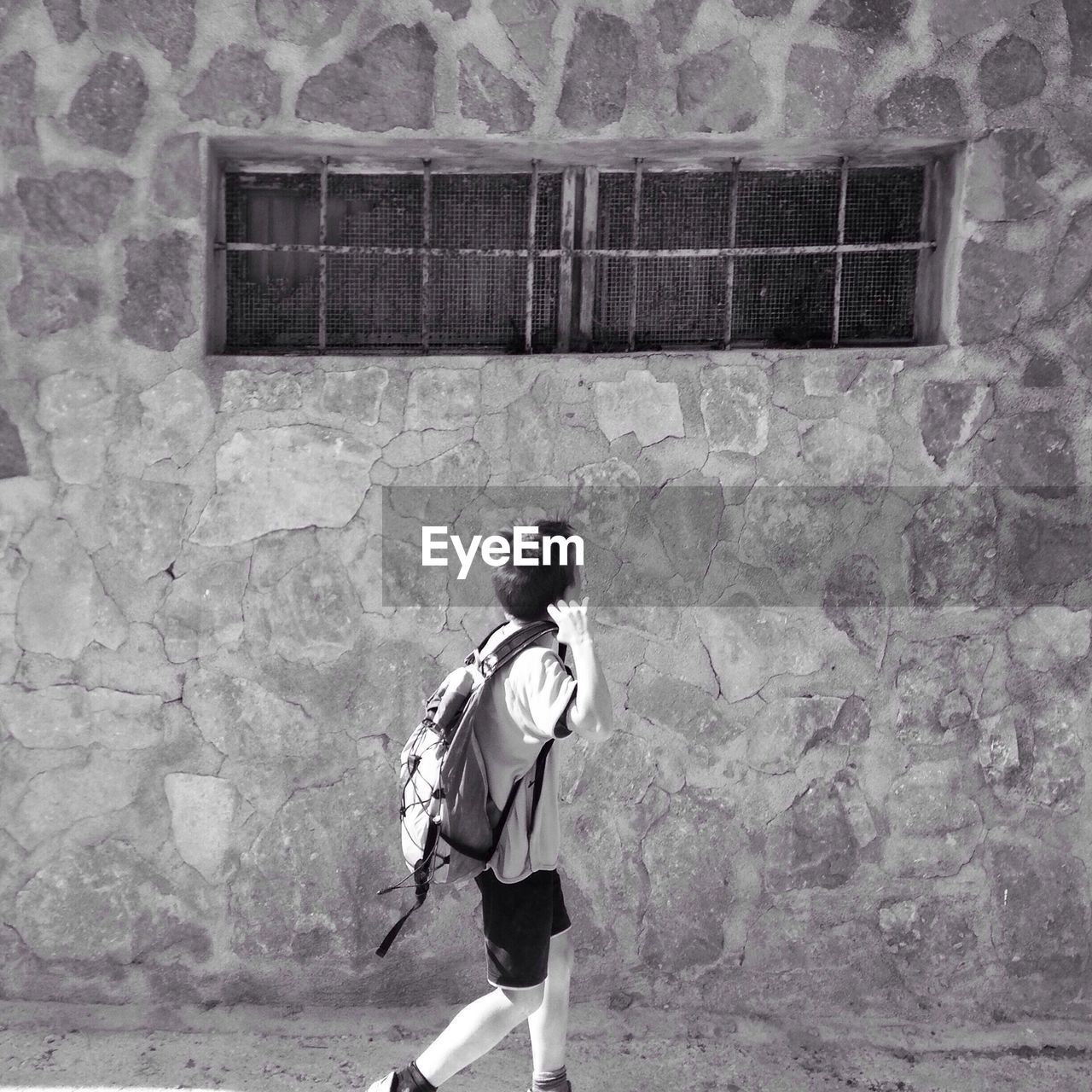 REAR VIEW OF YOUNG WOMAN STANDING AGAINST WALL