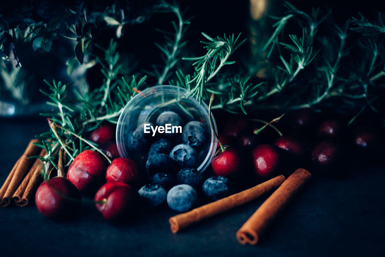 Close-up of fruits with rosemary and cinnamons on table