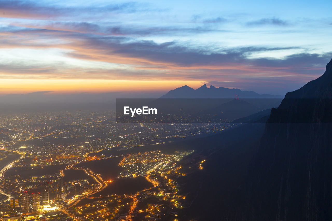 AERIAL VIEW OF ILLUMINATED CITY BUILDINGS AT SUNSET