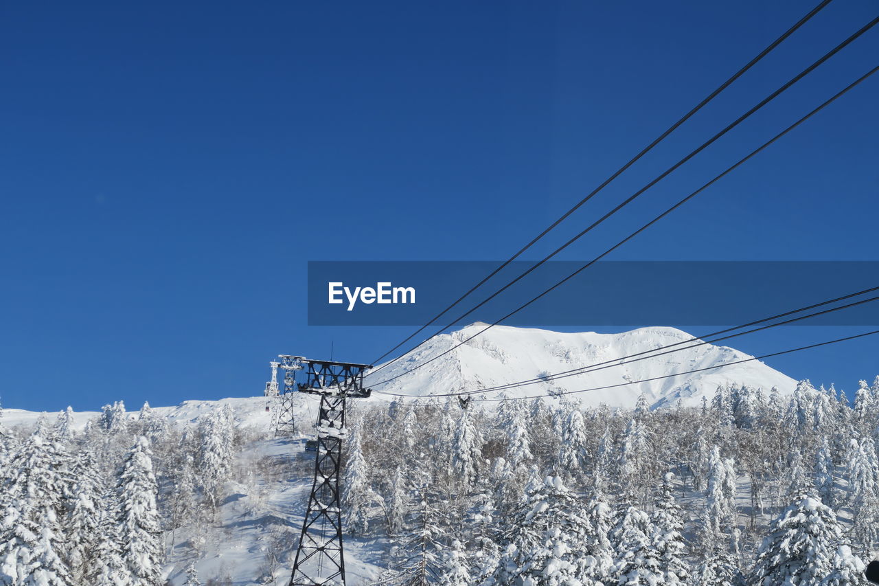 Low angle view of snow covered mountain against blue sky