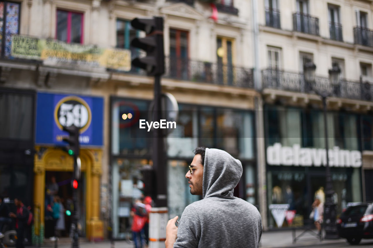 CLOSE-UP OF WOMAN STANDING ON STREET AGAINST CITY