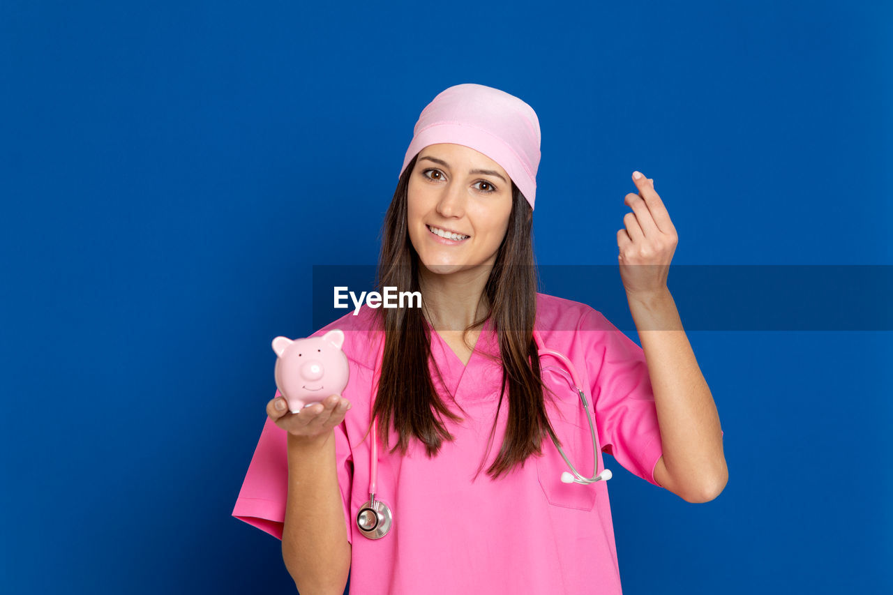 PORTRAIT OF HAPPY YOUNG WOMAN AGAINST BLUE BACKGROUND