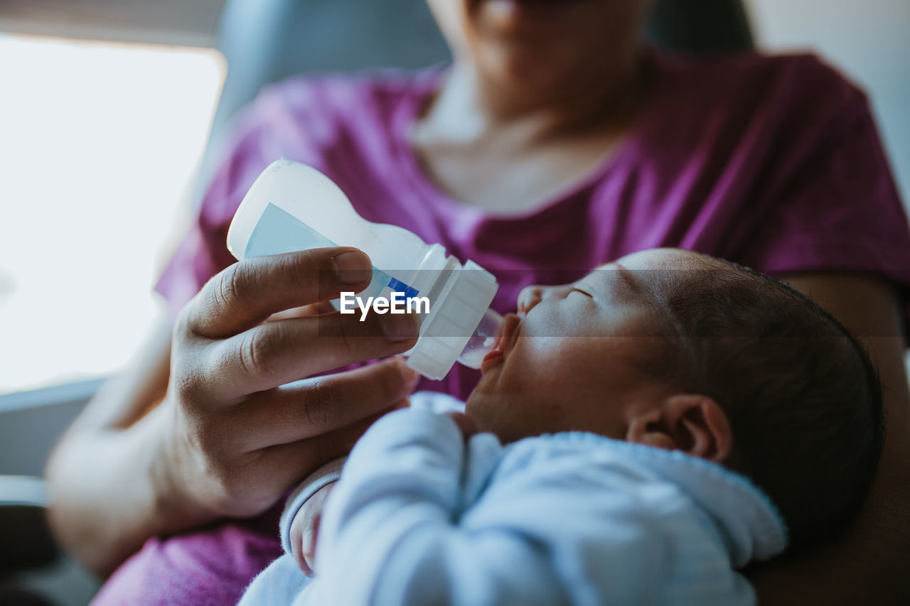 Midsection of mother feeding baby with bottle