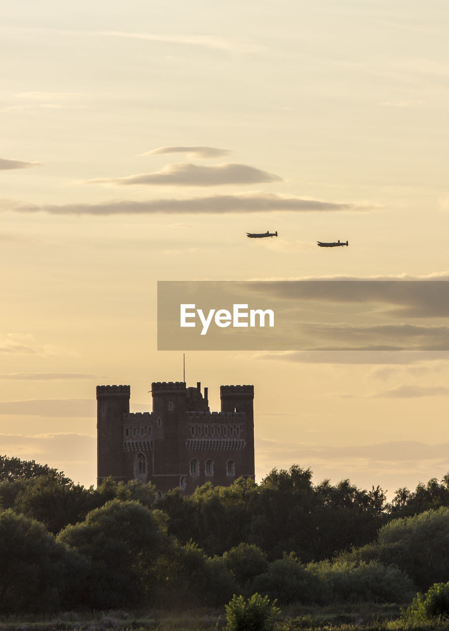 Airplanes flying over castle against sky