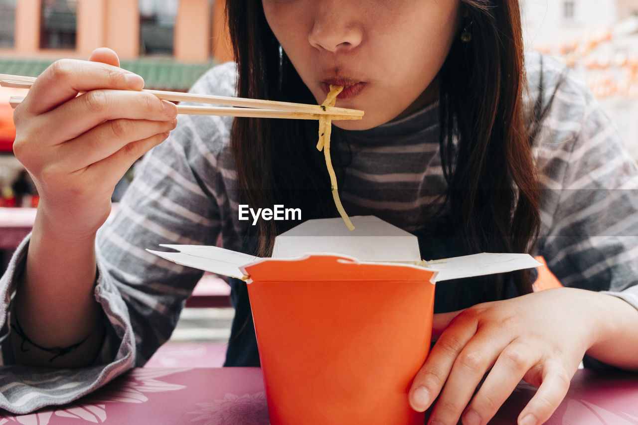 Woman eating noodles with chopsticks