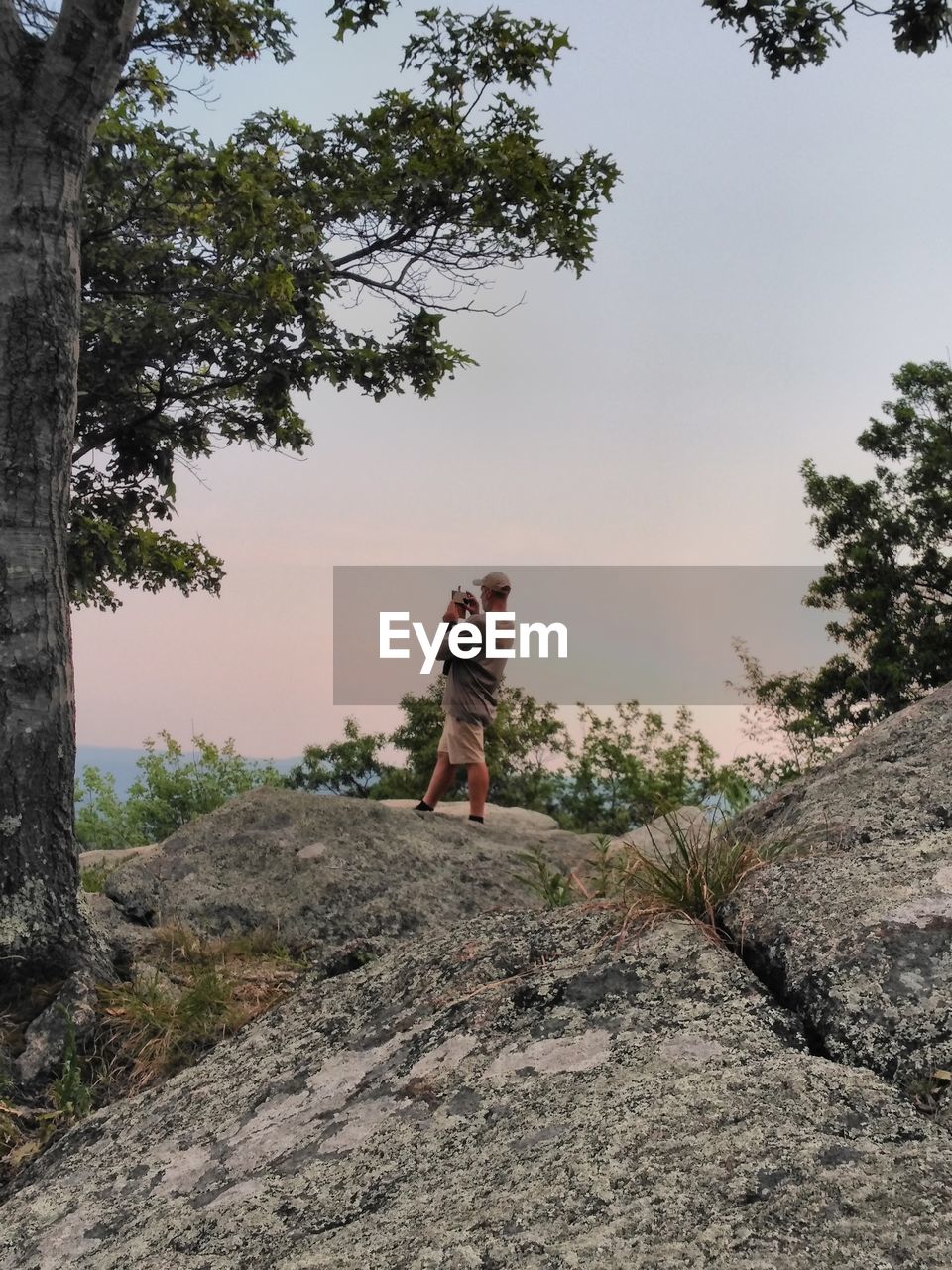 Man standing on rock against sky