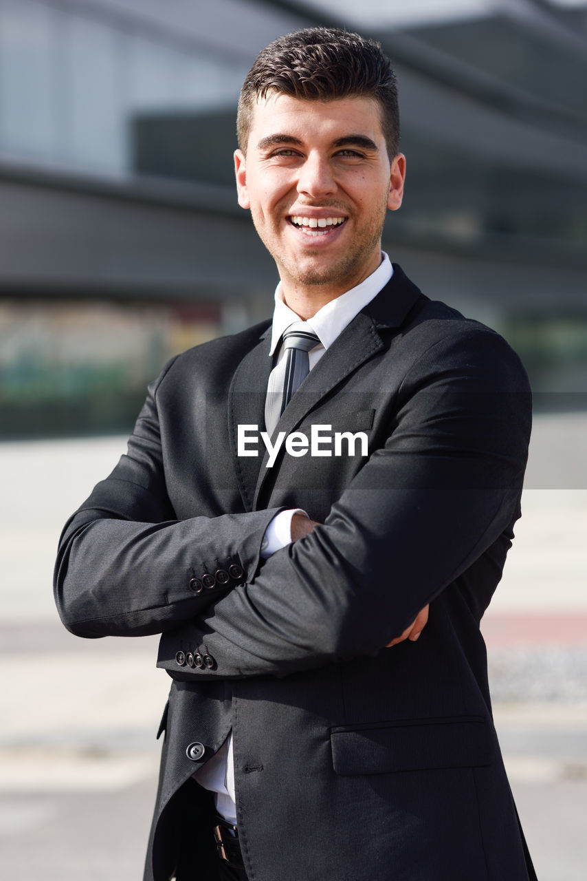 Portrait of happy young businessman standing on road