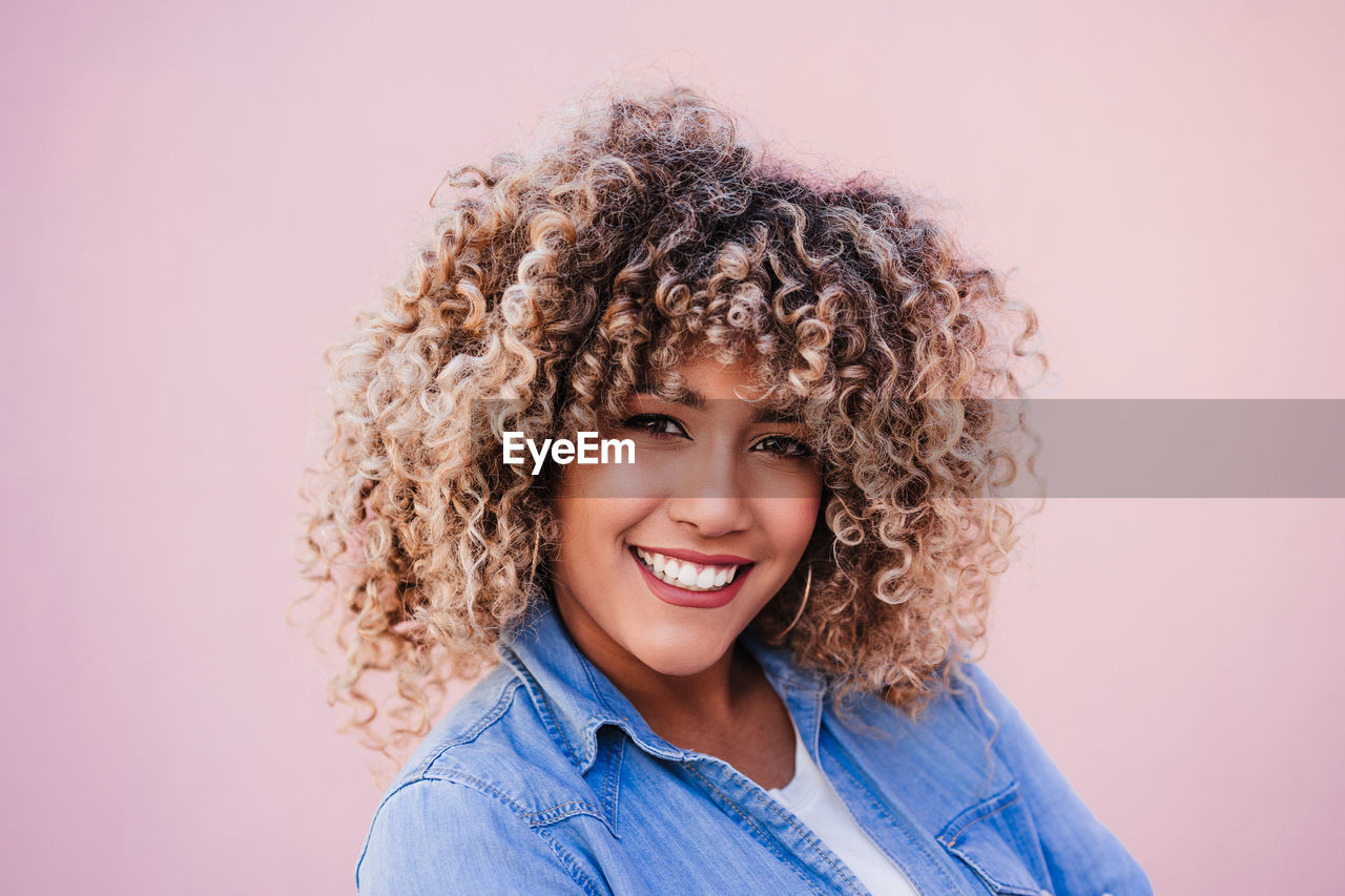 Portrait of smiling hispanic woman with afro hair in city during spring. urban lifestyle