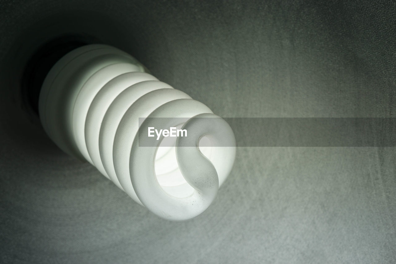 Low angle view of illuminated light bulb against wall