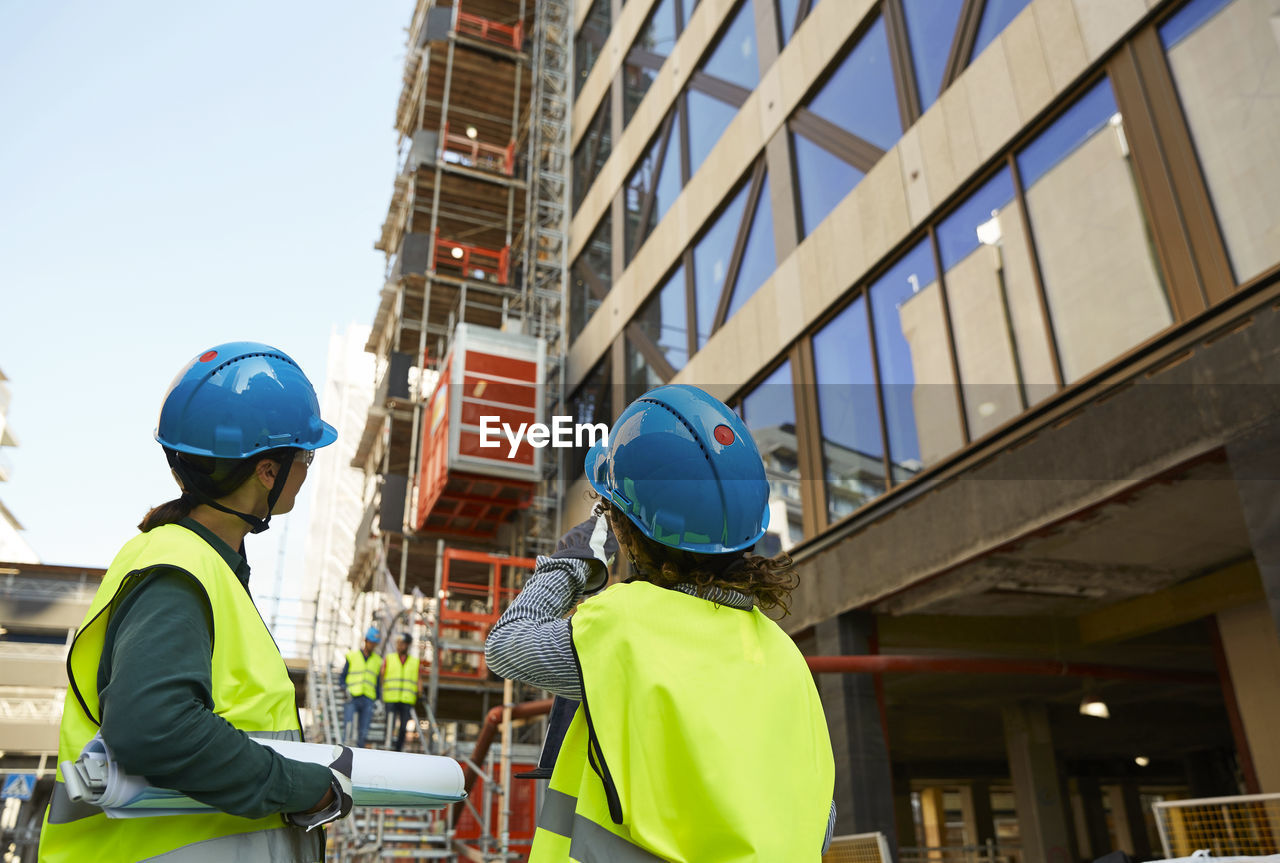 Female engineers in reflective clothing discussing at construction site