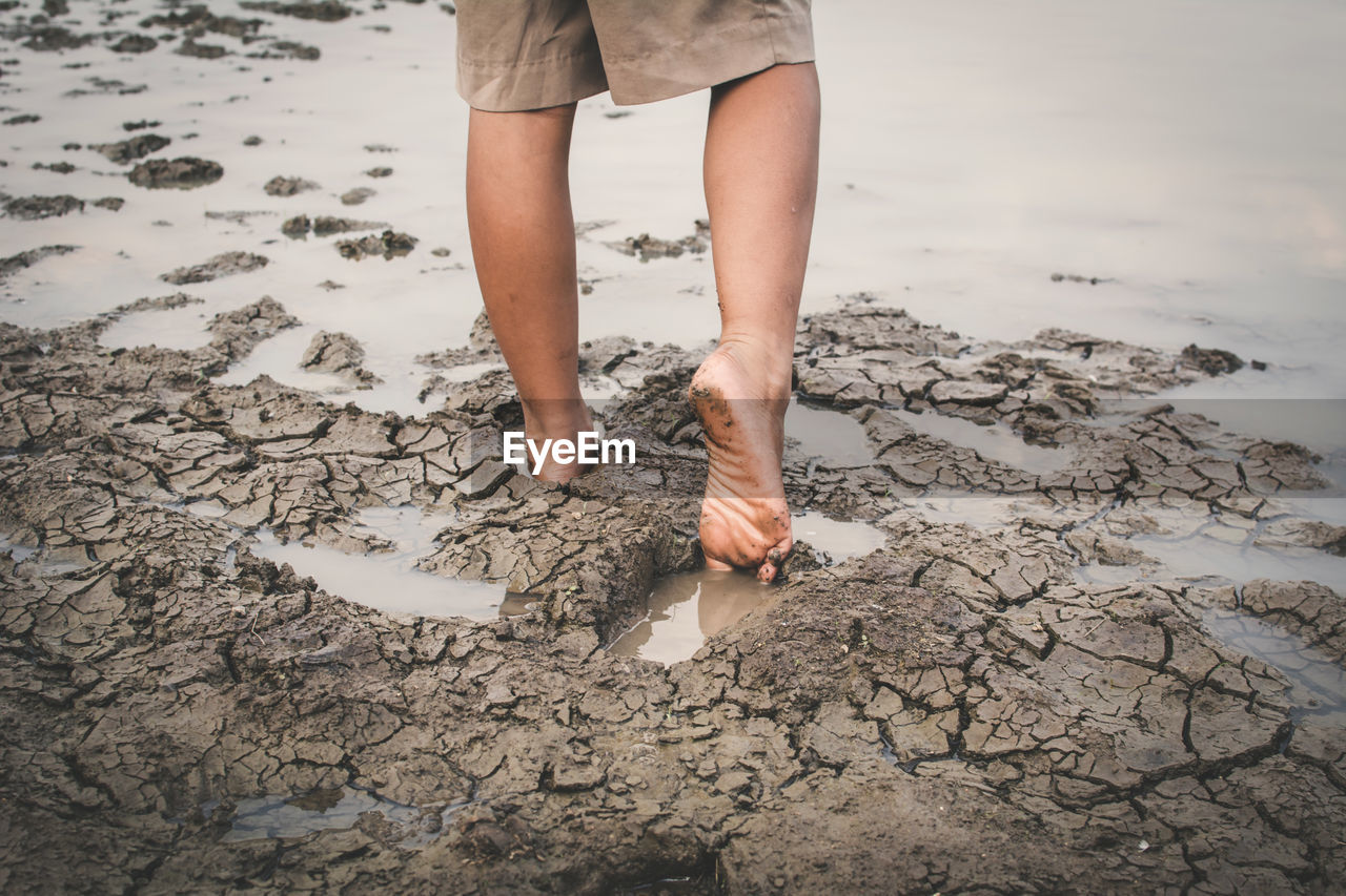 Low section of boy walking on mud