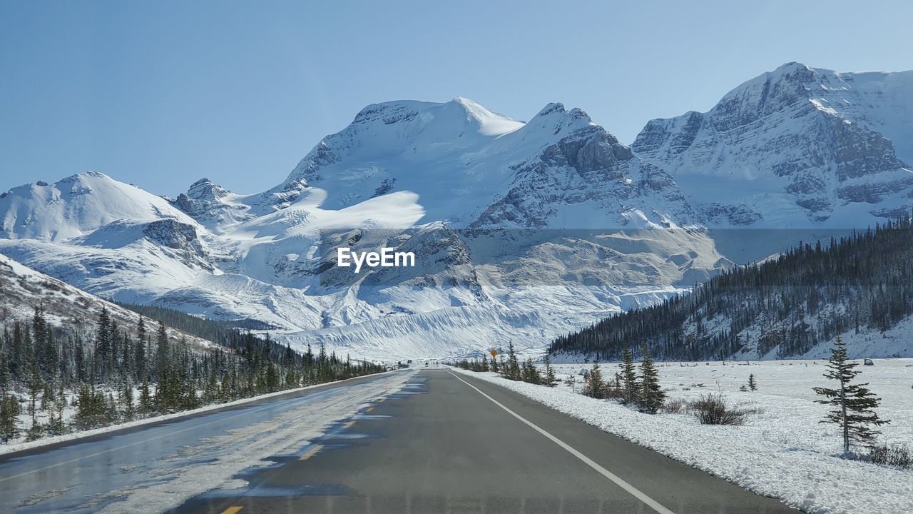 Road amidst snowcapped mountains against sky