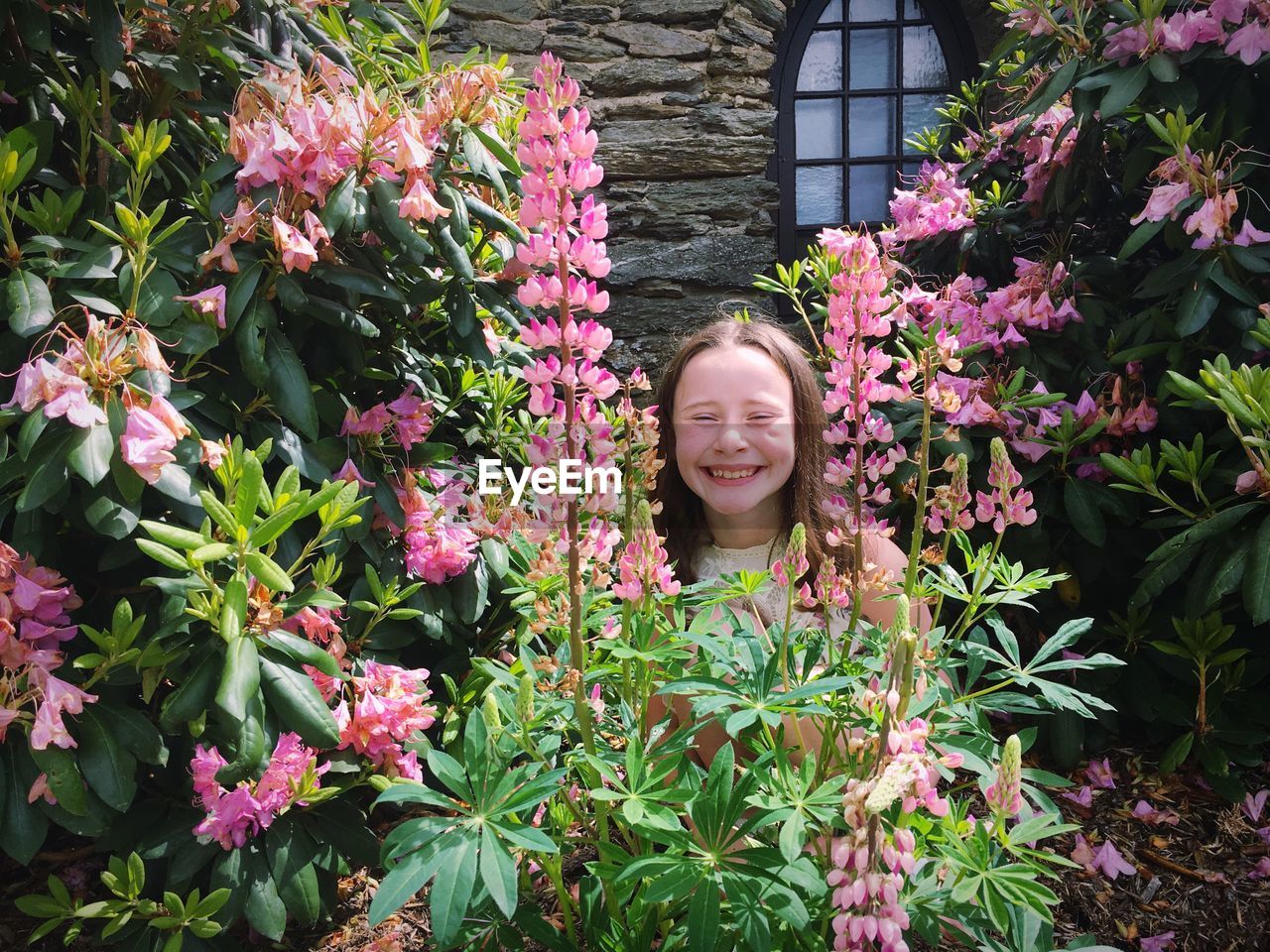 Portrait of smiling girl standing amidst pink flowers in park