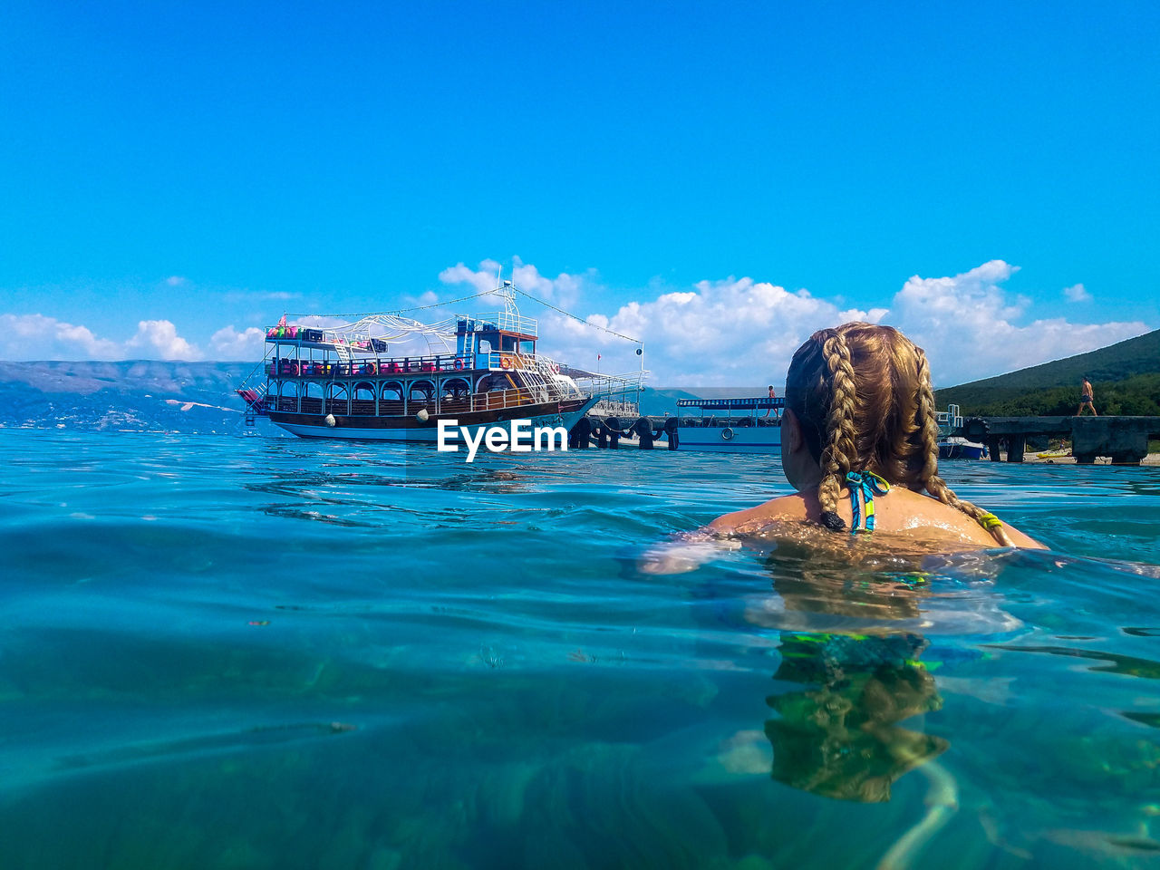 Rear view of woman swimming in sea against sky during sunny day