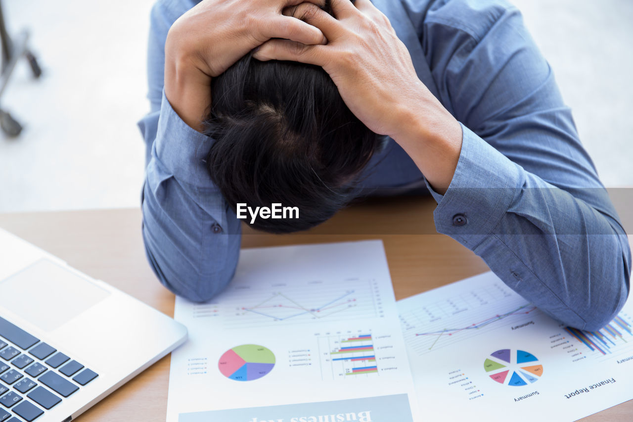 High angle view of frustrated businessman with head in hands