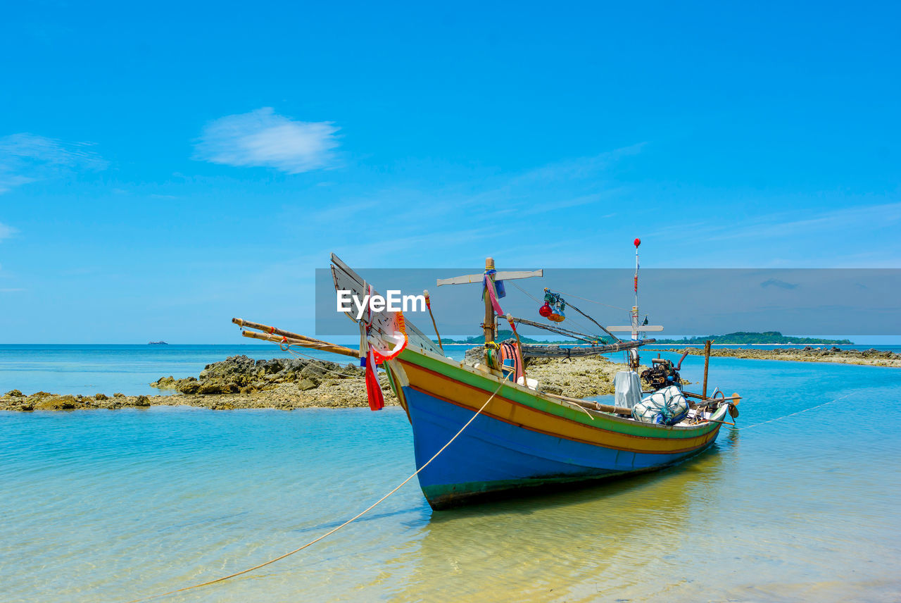 BOATS MOORED AT BEACH AGAINST BLUE SKY