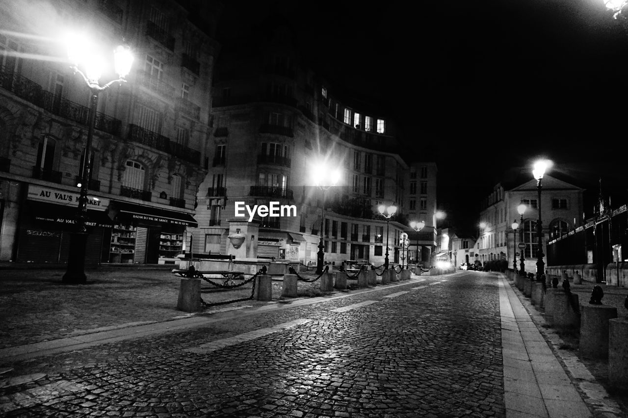 Illuminated street amidst buildings at night