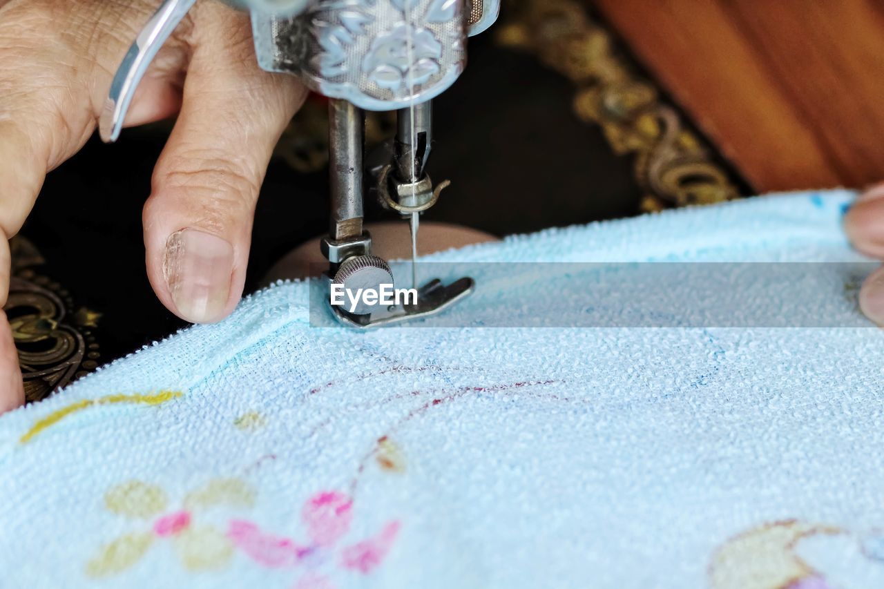 Cropped hand of tailor using sewing machine