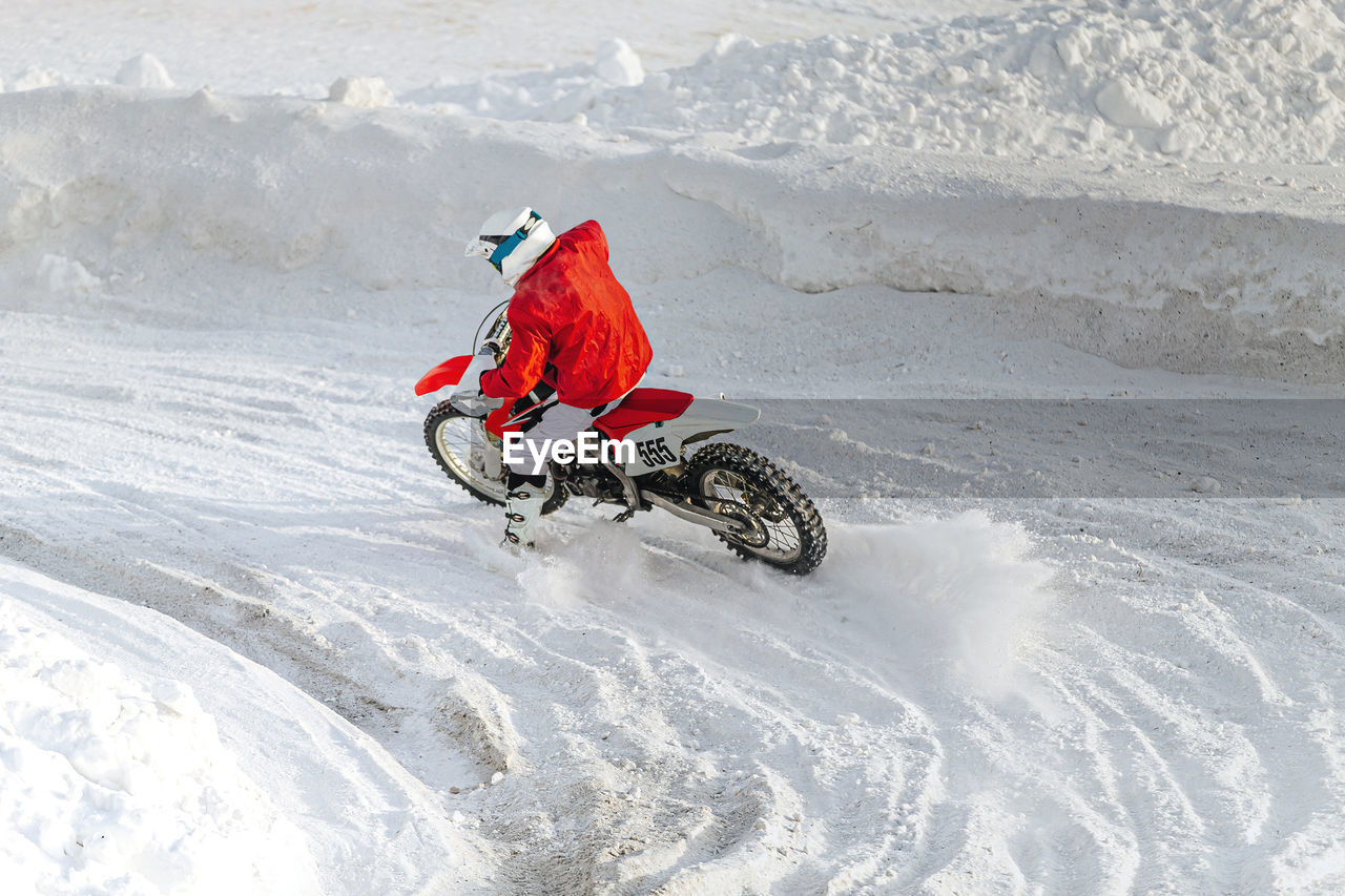 Motorcycle racer on motorcycle riding snowy turn