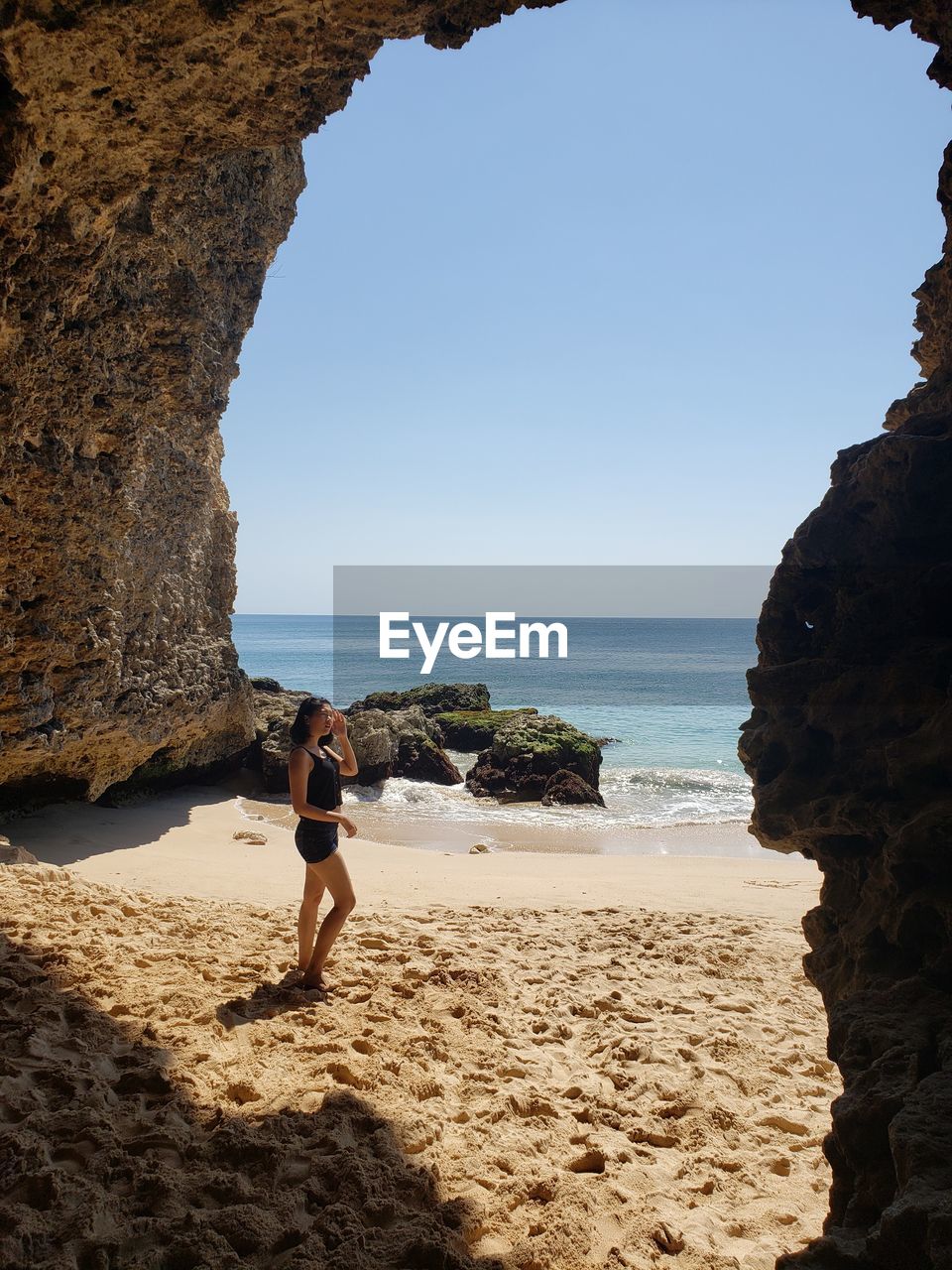 Rear view of woman standing at beach against sky