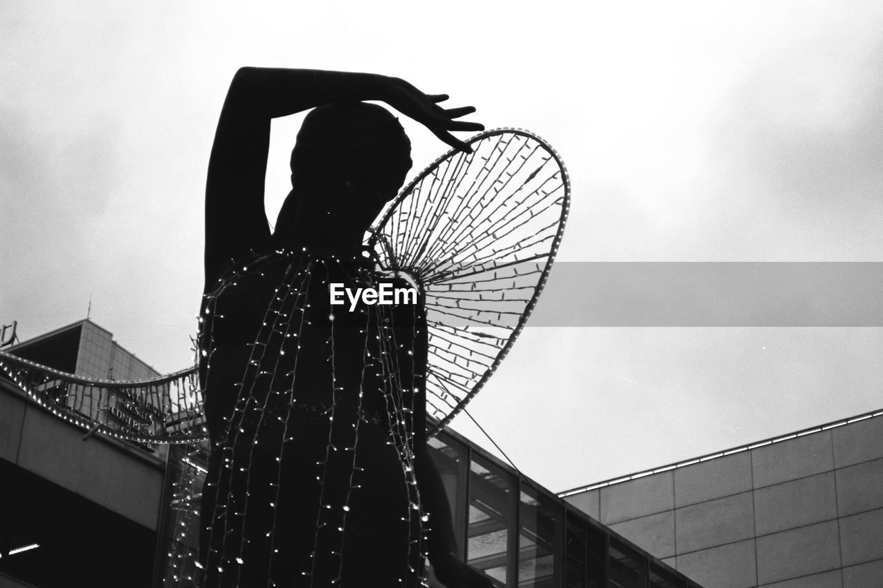LOW ANGLE VIEW OF SILHOUETTE PERSON AGAINST FERRIS WHEEL