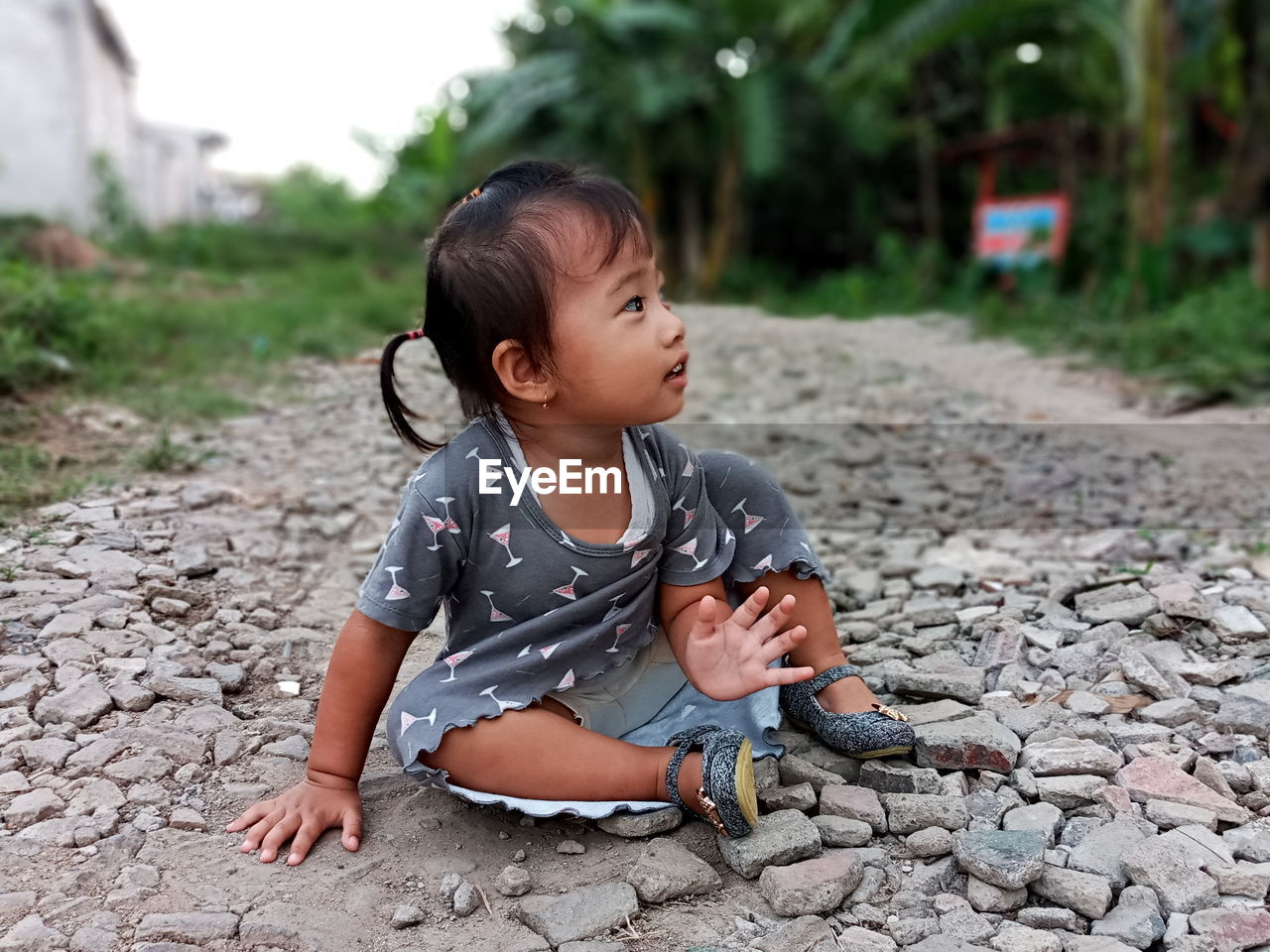 Full length of cute baby girl sitting on stones