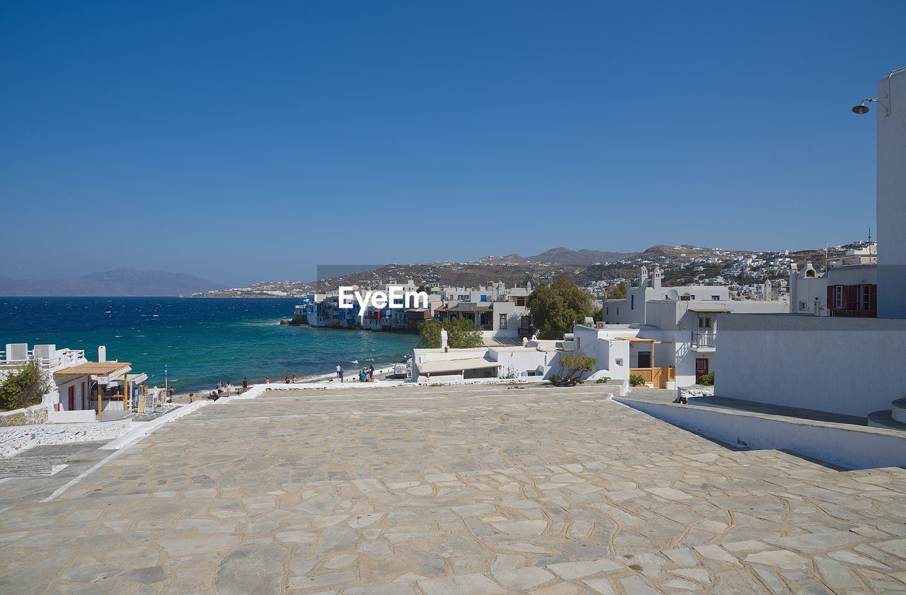 Town by sea against clear blue sky