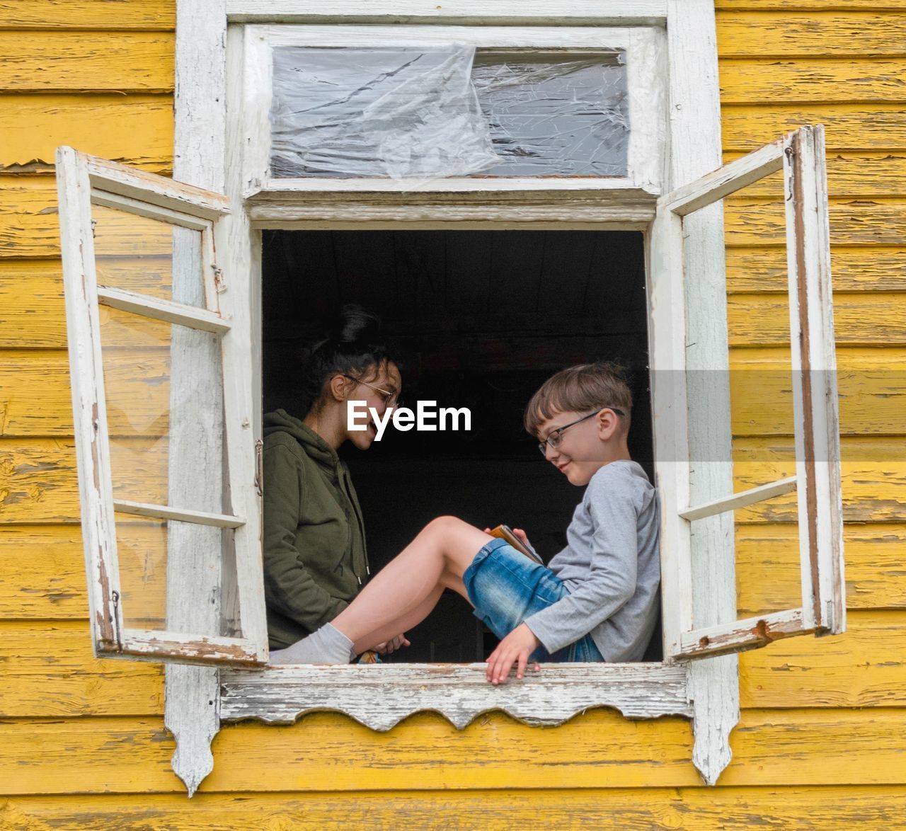 Portrait of two siblings at home near opened window