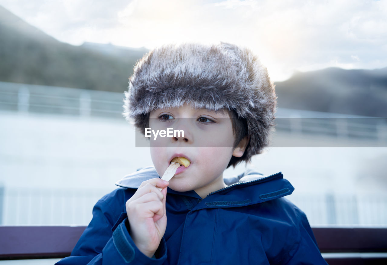 Close-up of boy looking away while eating food outdoors