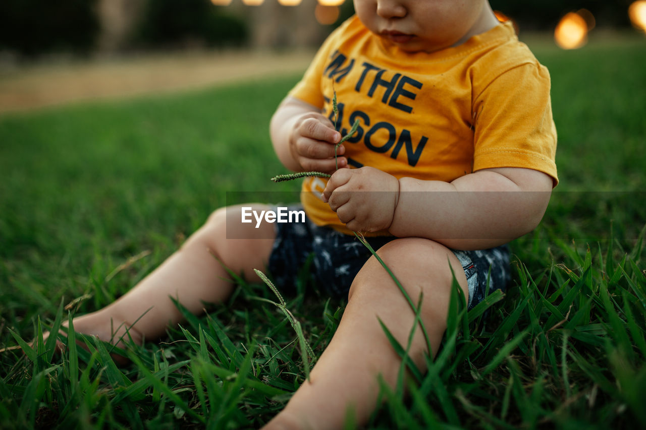 Midsection of boy sitting on field