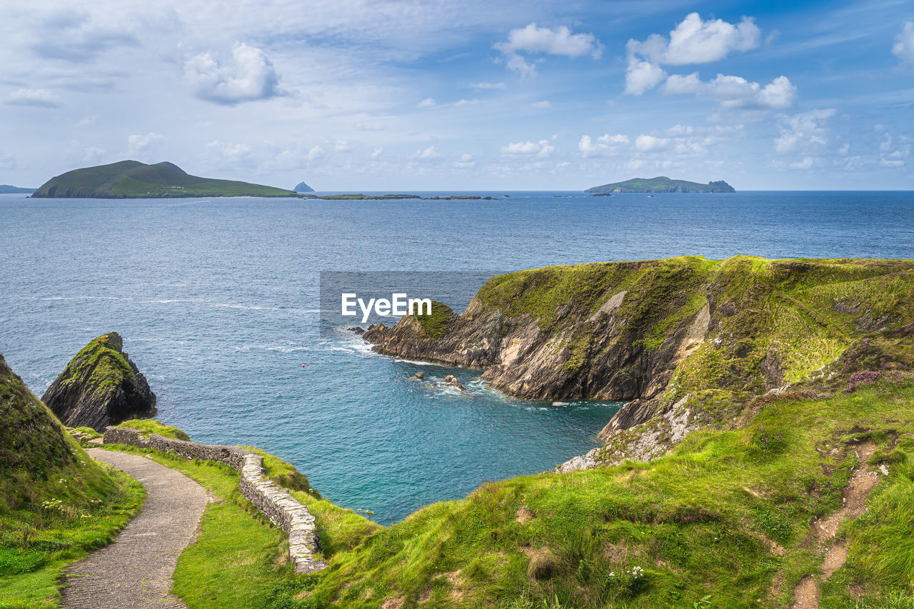 Path leading to dunquin pier surrounded by turquoise water of atlantic ocean,  ireland
