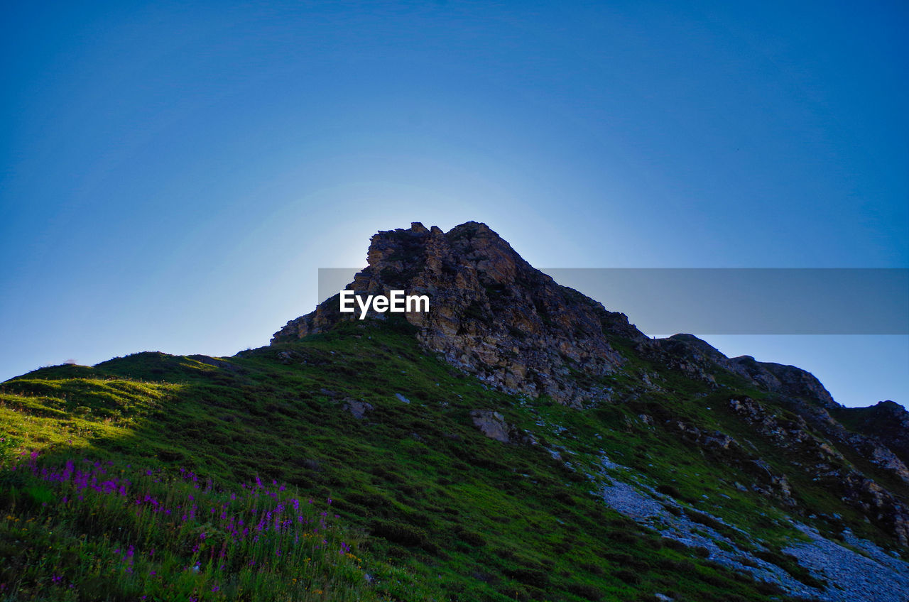 Low angle view of mountain against clear blue sky