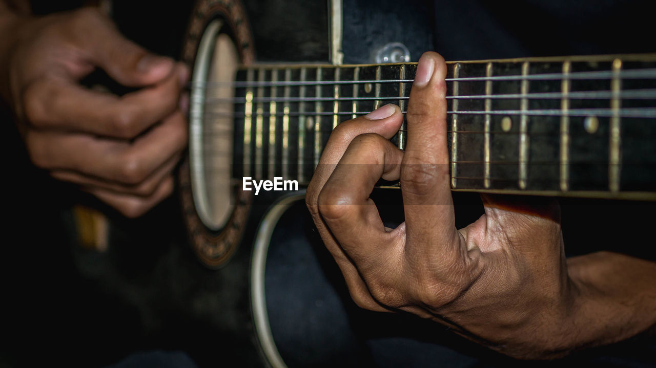 MIDSECTION OF MAN PLAYING GUITAR IN THE CAMERA