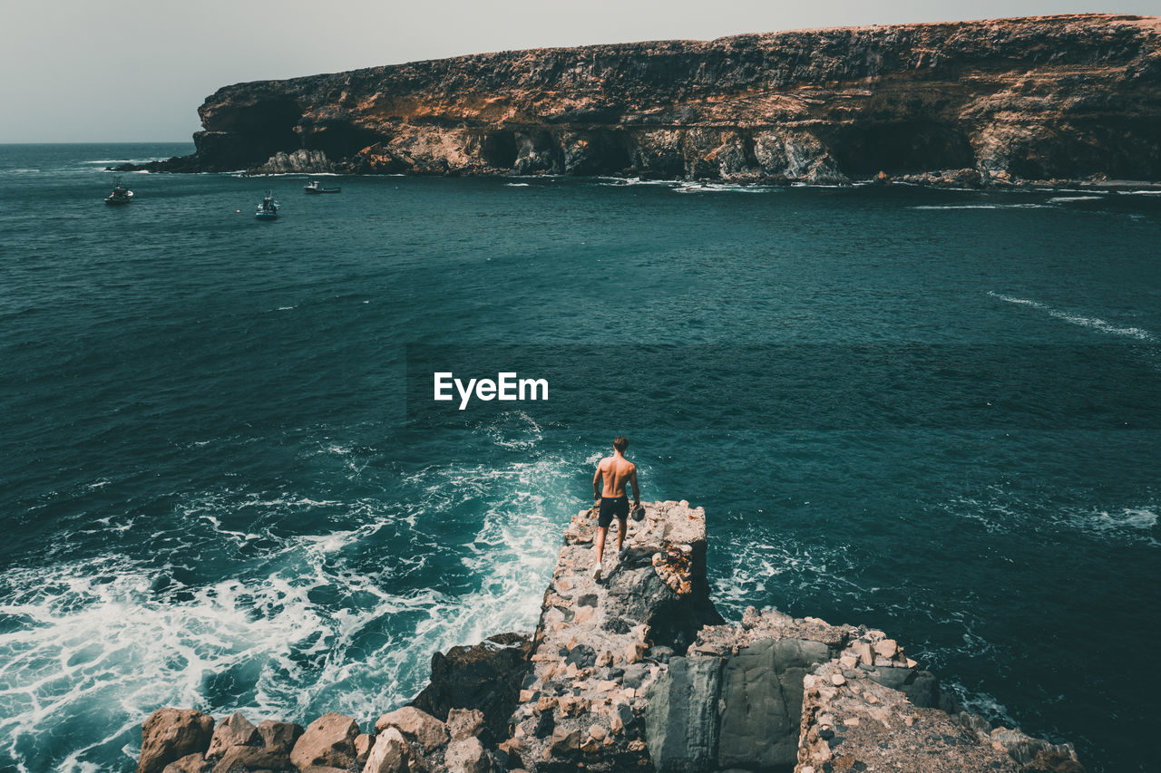 High angle view of man walking on rock formation against sea