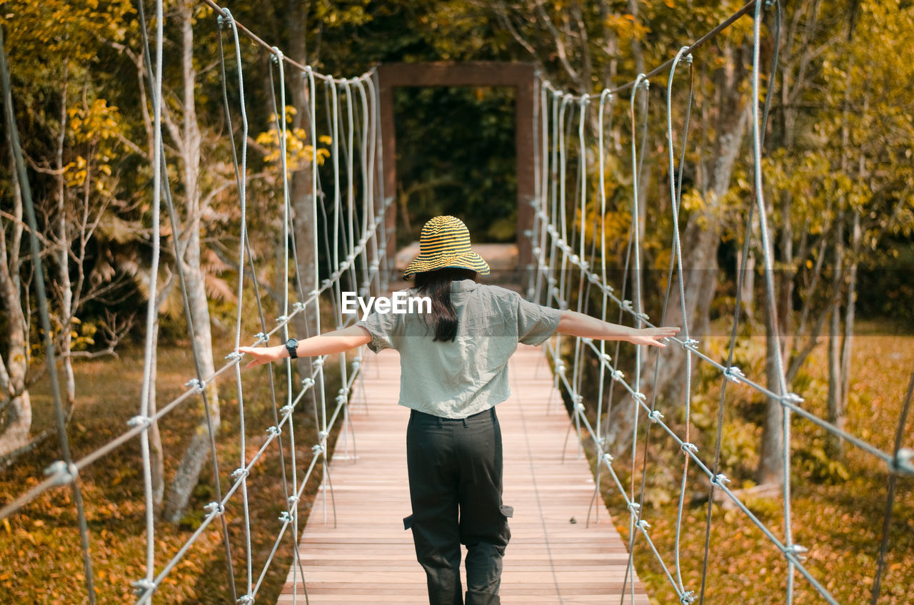 Rear view of woman standing on footbridge