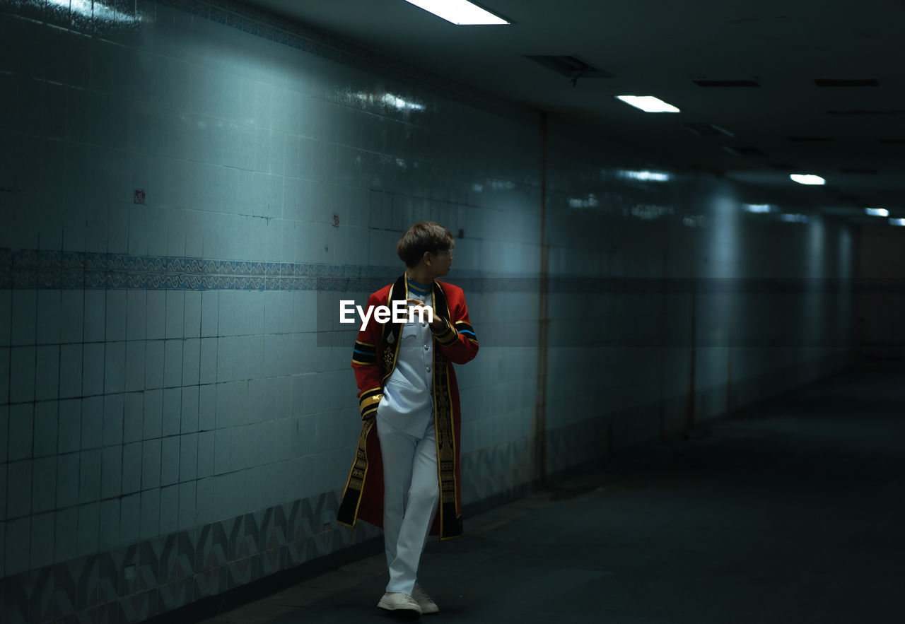 Side view of man standing in illuminated subway