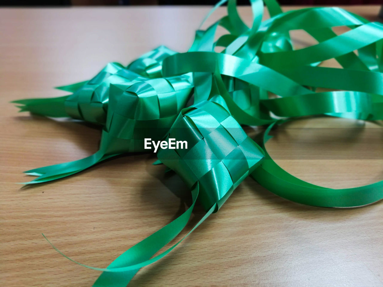 HIGH ANGLE VIEW OF GREEN PAPER ON WOODEN TABLE