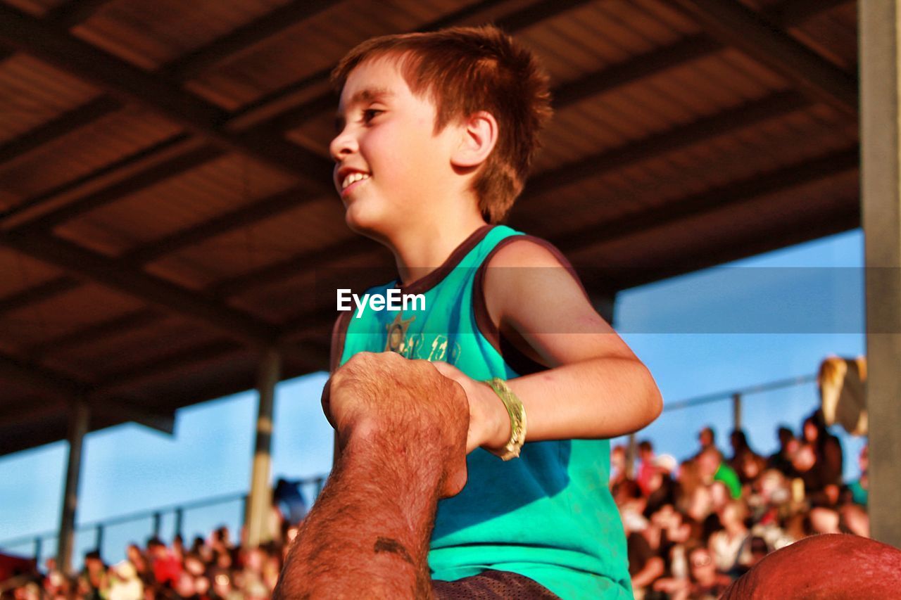 Low angle view of smiling boy at bleachers