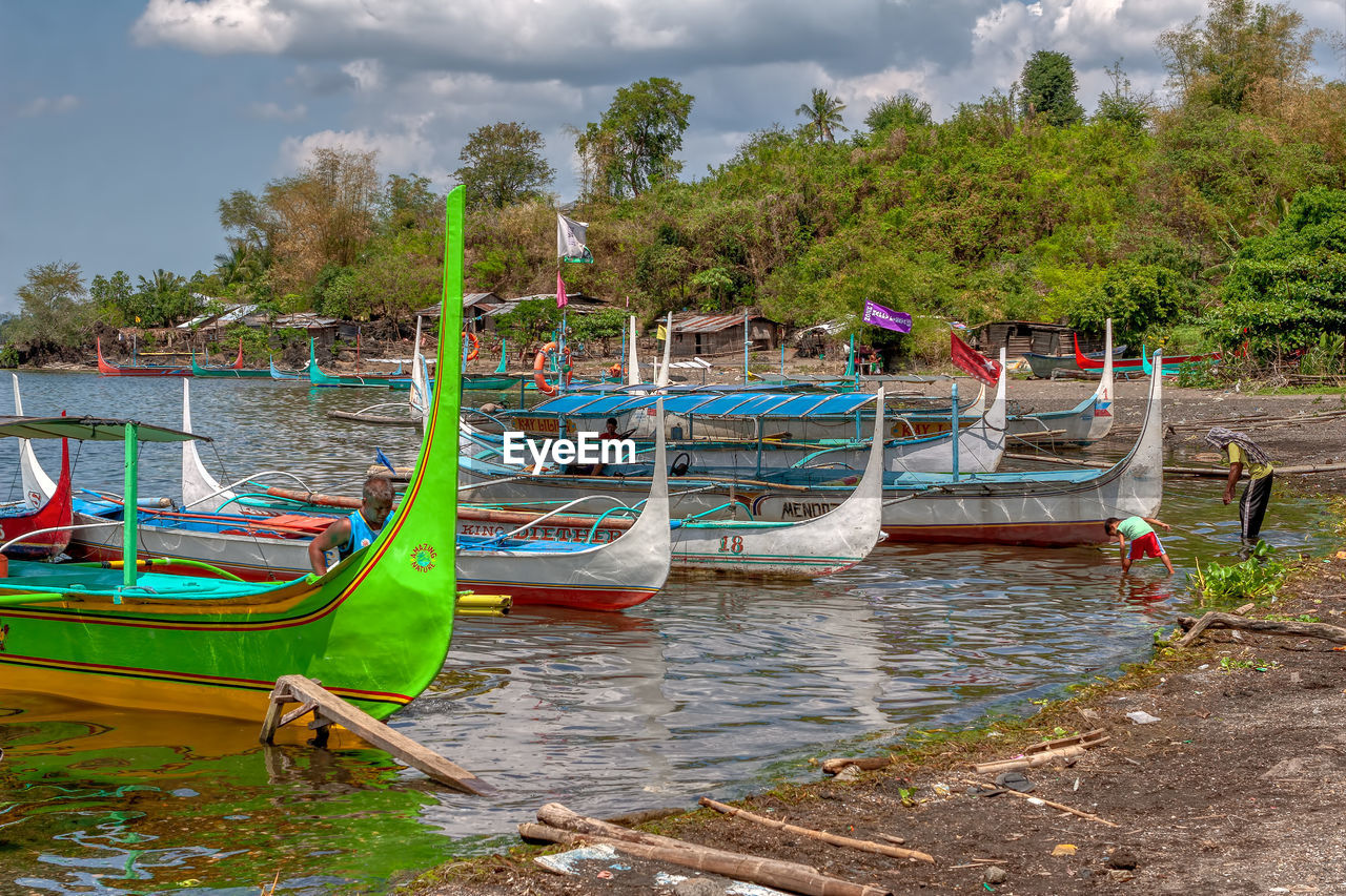 Boats moored on shore against sky
