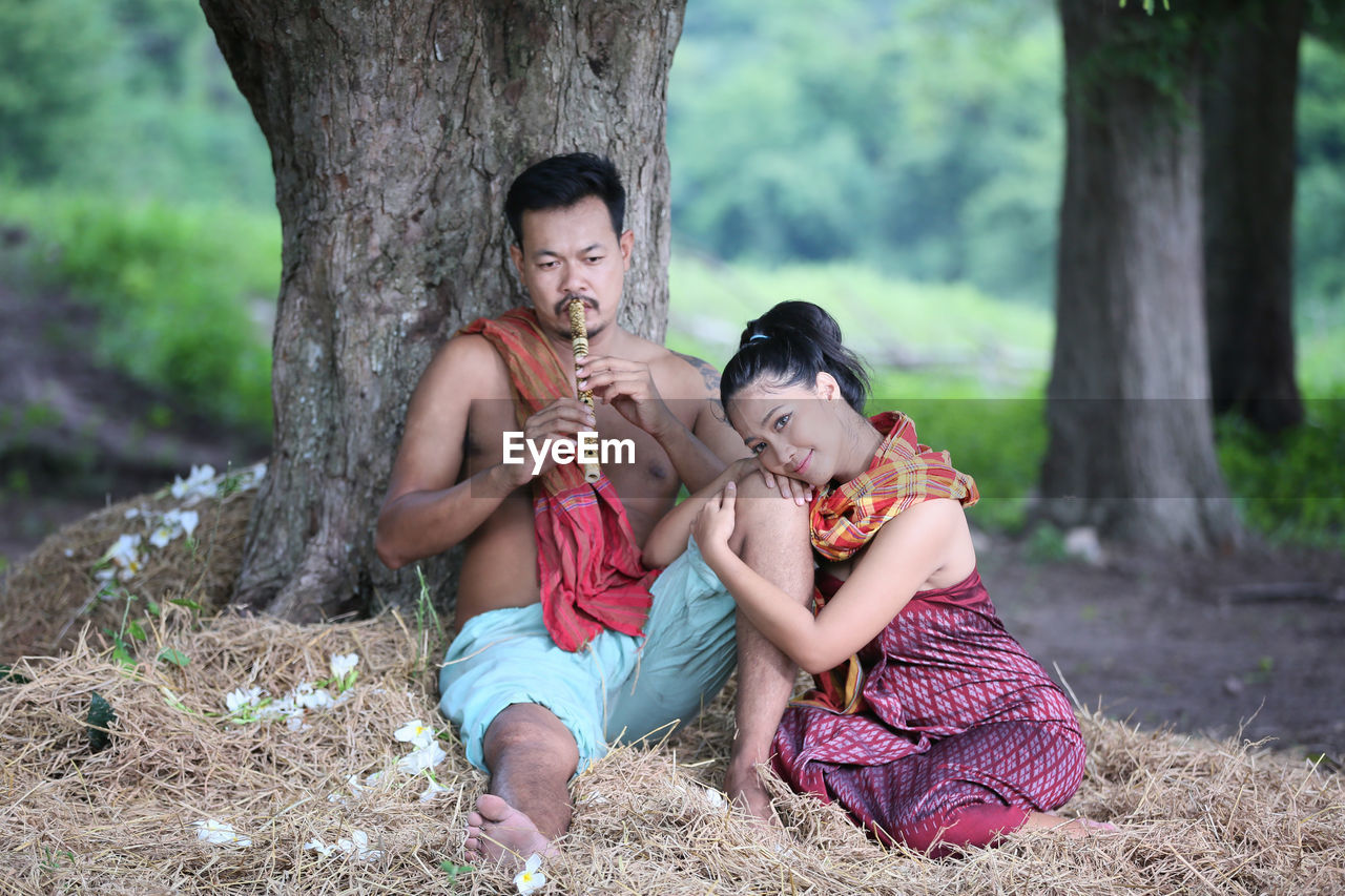 Full length of woman sitting on tree trunk