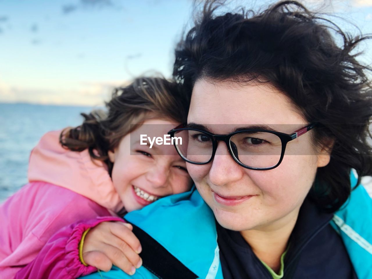 Portrait of smiling mother and daughter against sea