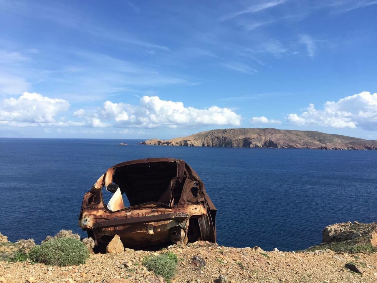 Abandoned car on shore against sky